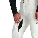 White snow pants with a black spider logo on a white background