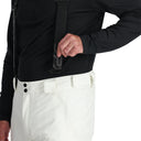 Person wearing a black jacket and white pants on a white background