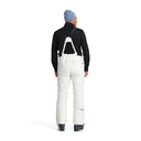 Person wearing a black jacket, white pants, and a blue beanie on a white background
