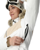 Person wearing a white and beige winter jacket with a fur-lined hood.