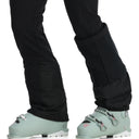 Person wearing light green ski boots with black pants on a white background